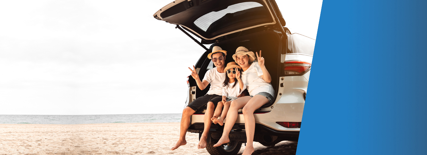 Asian family sitting in the back of their SUV on the beach